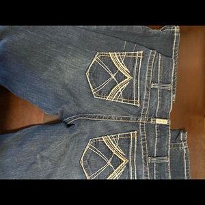 Ariat jeans tattered on back of bottom of leg